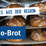 Bleche mit Brotlaiben sind gestapelt in einem Wagen.